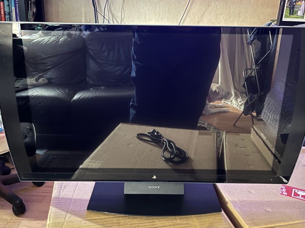 A very reflective small TV with a stand that says Sony
