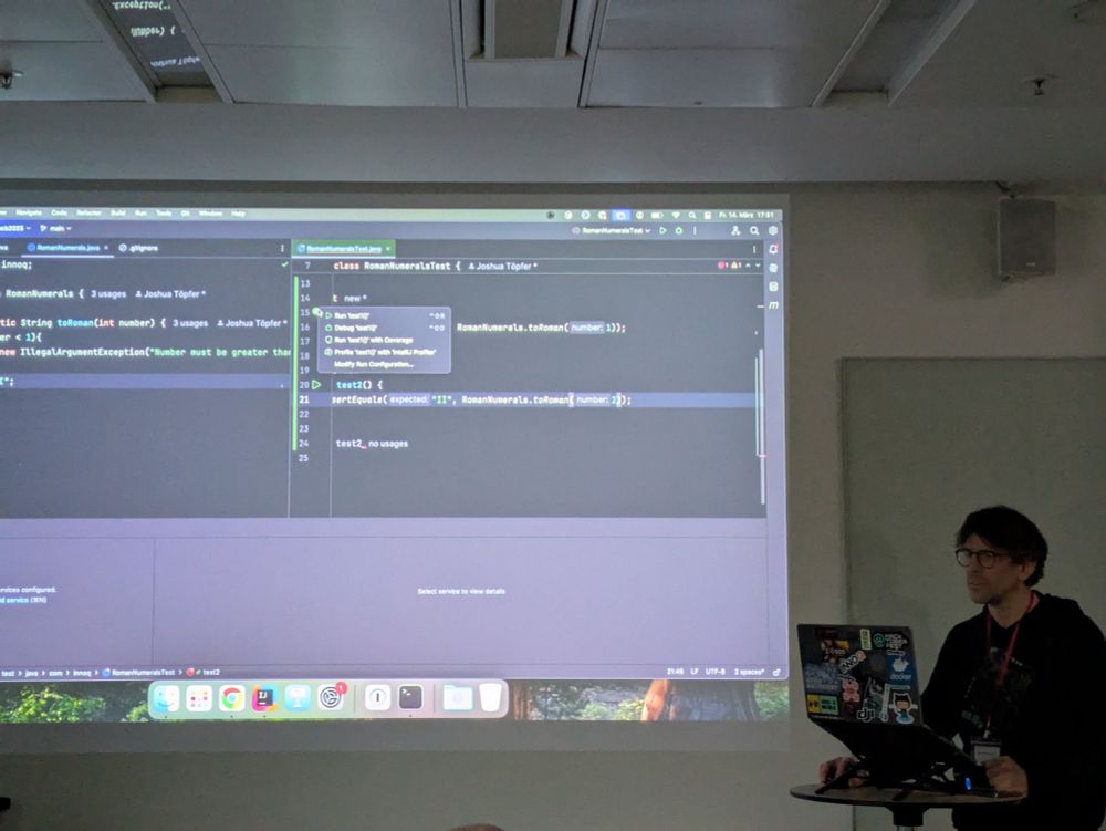 A person gives a presentation at a conference. Most of the image is taken up by a the big presentation on the wall.