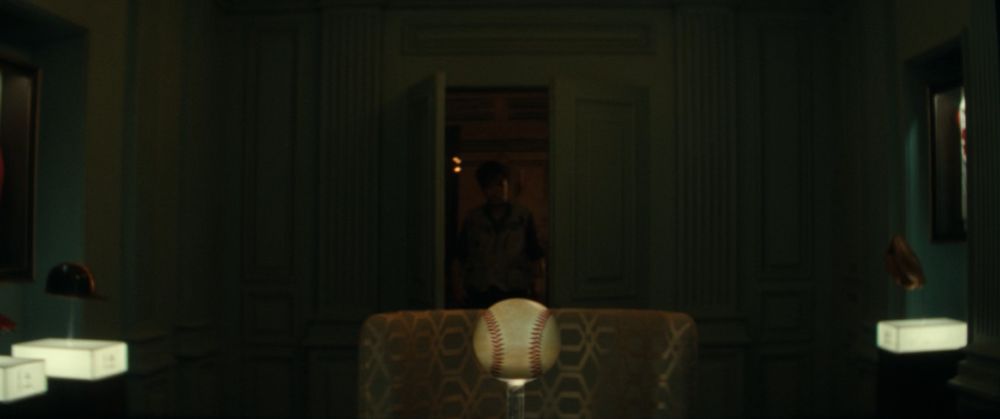 A screencap from Alien: Earth showing a character entering a room full of baseball memorabilia, with a baseball on a pedestal in the centre foreground