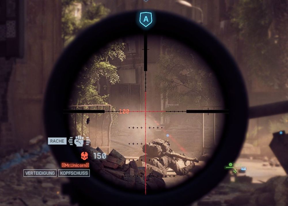 Screenshot aus einem Videospiel: Blick durch ein Sniper-Scope auf einen Verbündeten in einer urbanen Ruinenlandschaft. Das Fadenkreuz ist rot und zielt etwas über dem Verbündeten auf eine leere entfernte Wand. Eine eventuell durch den Schuss erzeugte Leiche ist unter dem Rauch am Boden nicht zu erkennen. Das HUD zeigt links unten "Rache", daneben eine erhobene Faust als Symbol. Darunter ein Totenkopf und der Name "Mr. Unicorn", darunter steht "Verteidigung" und "Kopfschuss"