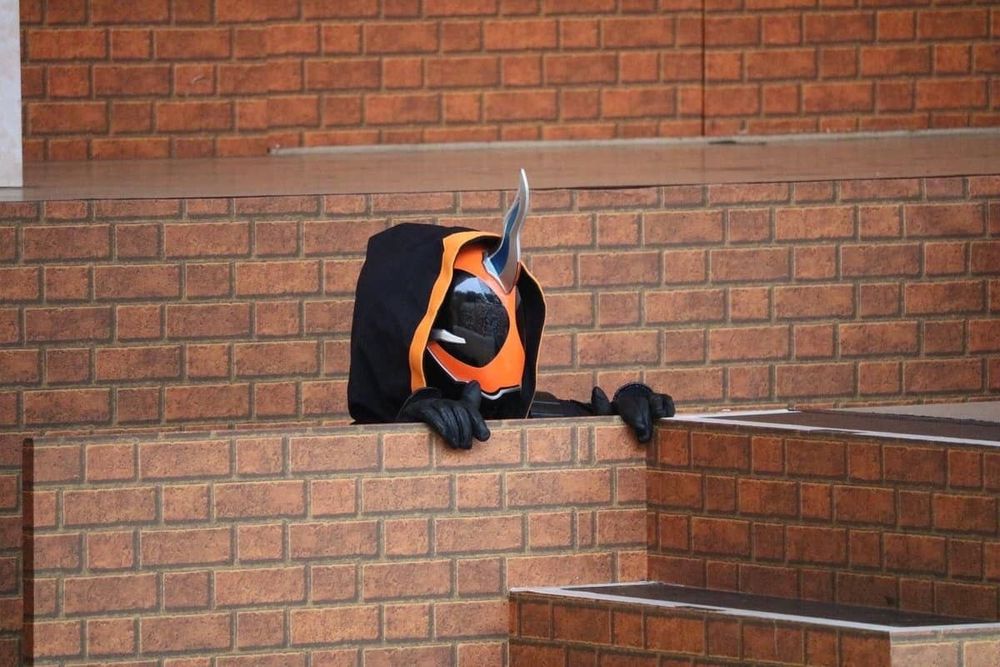 An image of kamen rider ghost peeking above a brick wall