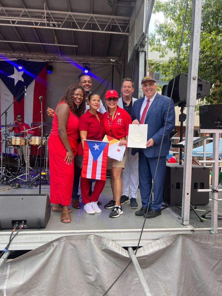 Councilor Santana with Councilors Flynn, Fitzgerald, Louijeune and Mejia with a Puerto Rican flag on the stage at the festival Betances with a Resolution recognizing Inquilinos Boricuas en Acción for their work in the community