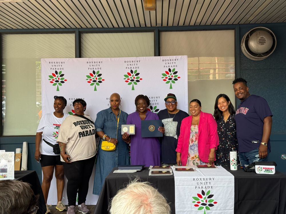 Councilor Santana with Toy Burton, Roxbury Unity Parade Organizer, Representative Ayanna Pressley, Councilor Louijeune, Mayor Wu and Representative Liz Miranda in front of a Roxbury Unity Day back drop