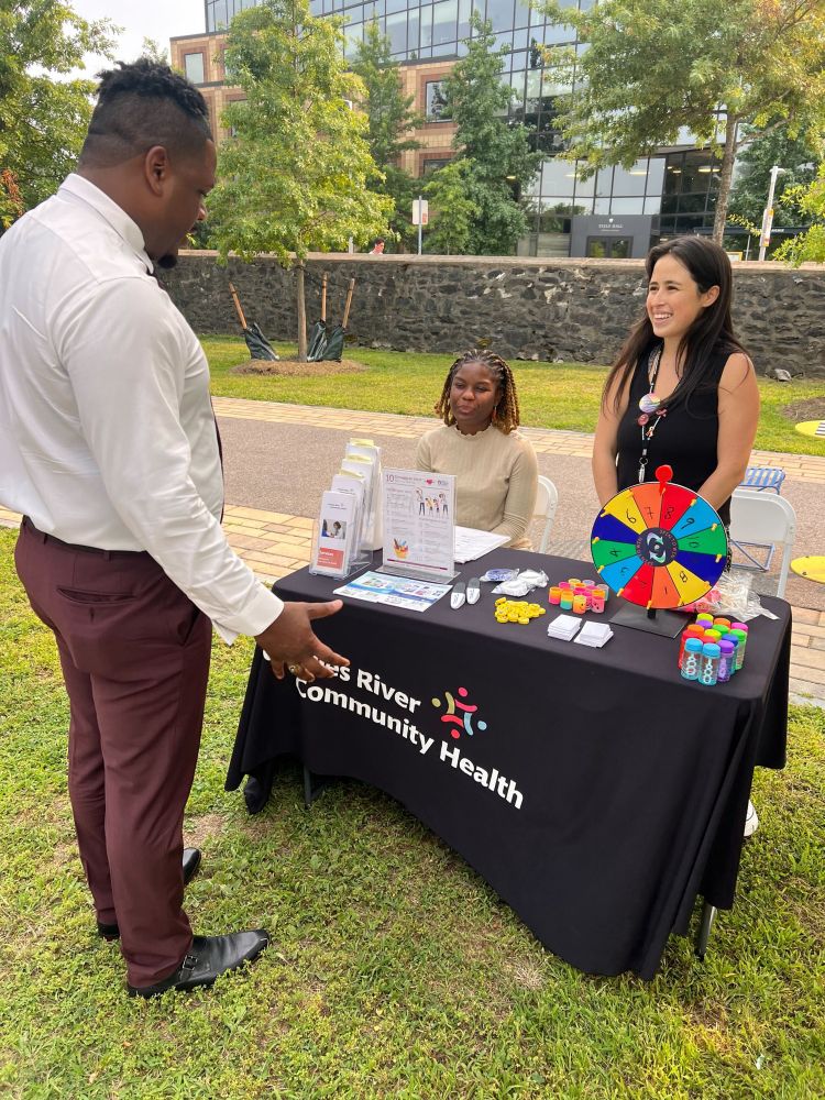 Councilor Santana spins the wheel at the community resource table for Charles River community health