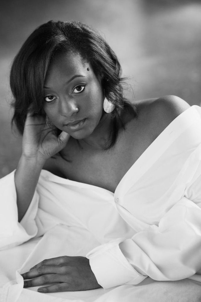 B&W photo of Black lady in a man’s dress shirt. 