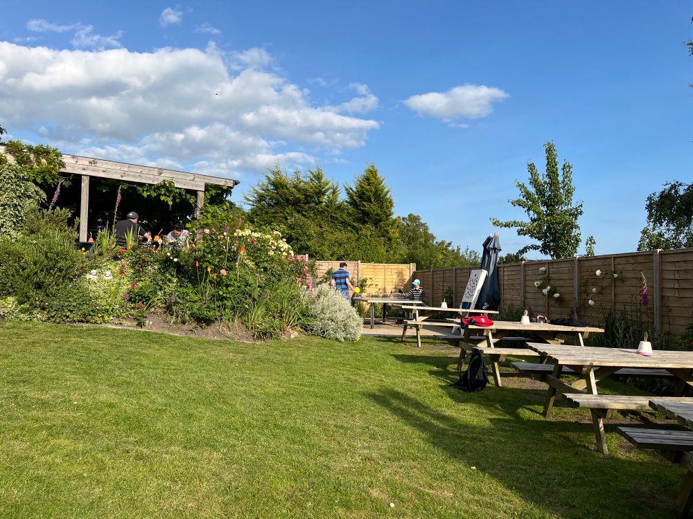 The garden of our local pub, with tables, wonderful flowers and also blue skies and sun