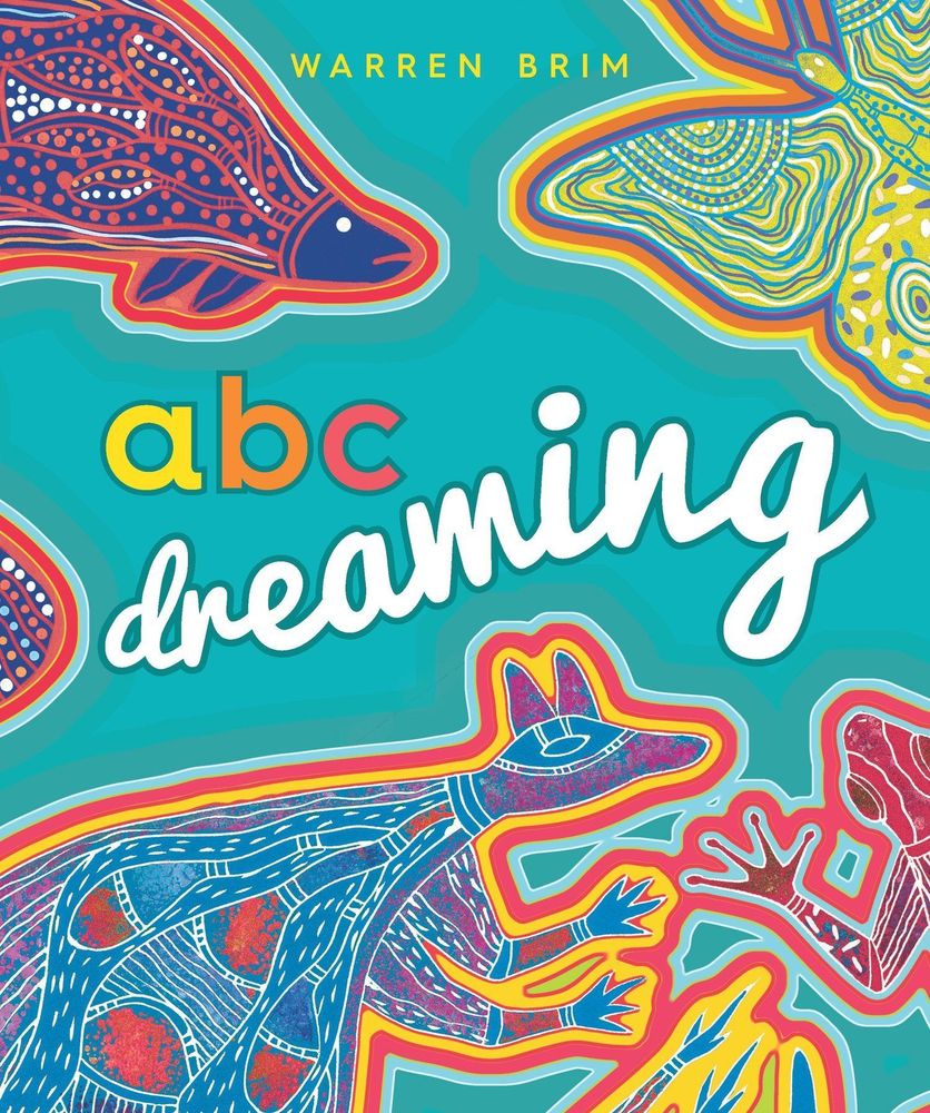 The cover of a children’s picture book titled ABC Dreaming by Warren Brim. Brightly coloured, stylised illustrations of a wallaby, red-eyed green tree frog, barramundi, and Ulysses butterfly, against a vivid teal background.