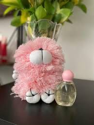 Guguzinho rosa de fiapo com um frasco de giovanna baby ao lado