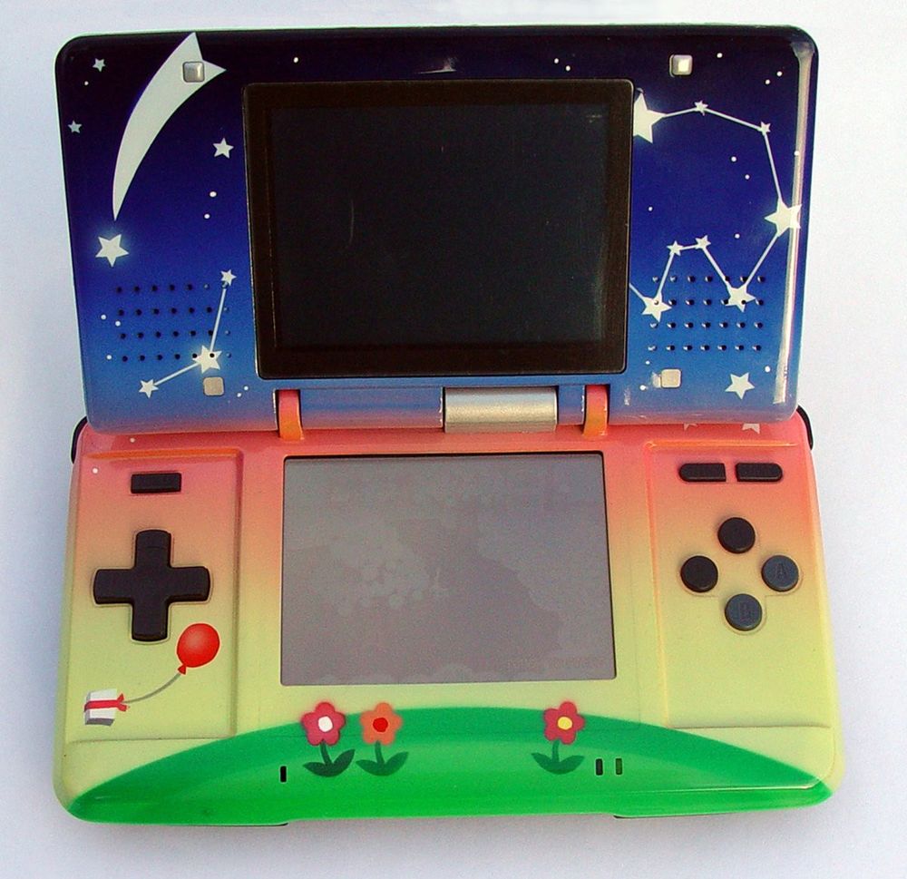 The interior of the DS has a starry sky print with shooting stars and constellations and a gradient that goes dark to light for the top shell. The bottom shell has a sunset gradient going dark to light, a balloon with a present, and a grassy hill with flowers at the bottom.