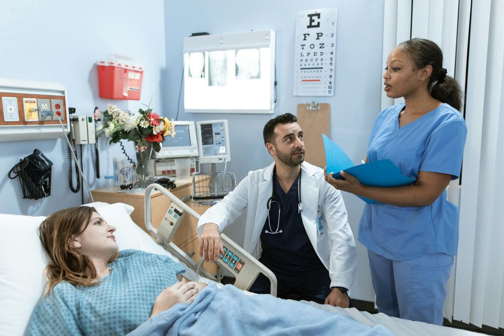 A doctor and a nurse next to a patient who is lying in bed.