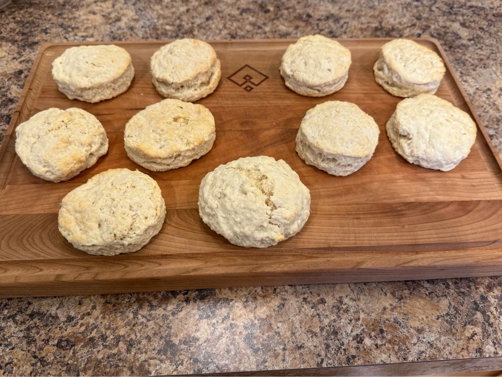 Wooden Cutting board on a counter with lightly golden biscuits 
