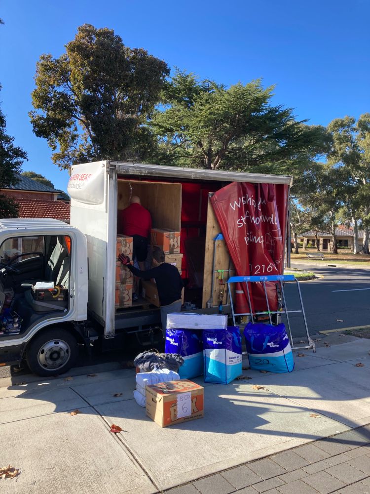 A removalist truck being loaded up with boxes and bags. 