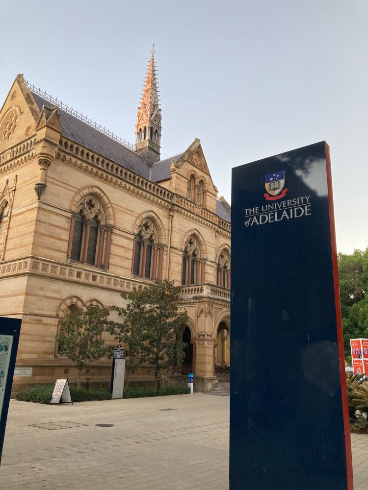 A photo of an old sandstone building on the city campus of the University of Adelaide, taken at dusk. 