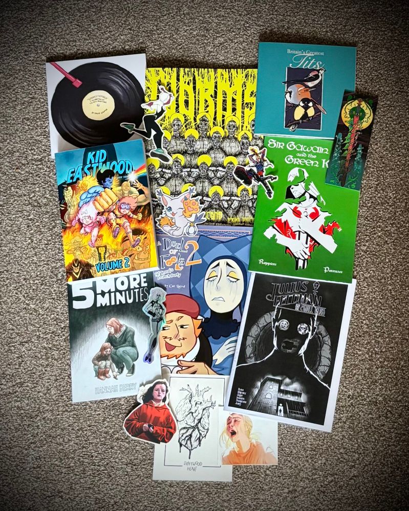 Photo of my con haul from Thought Bubble 2025 featuring comics, prints and stickers.