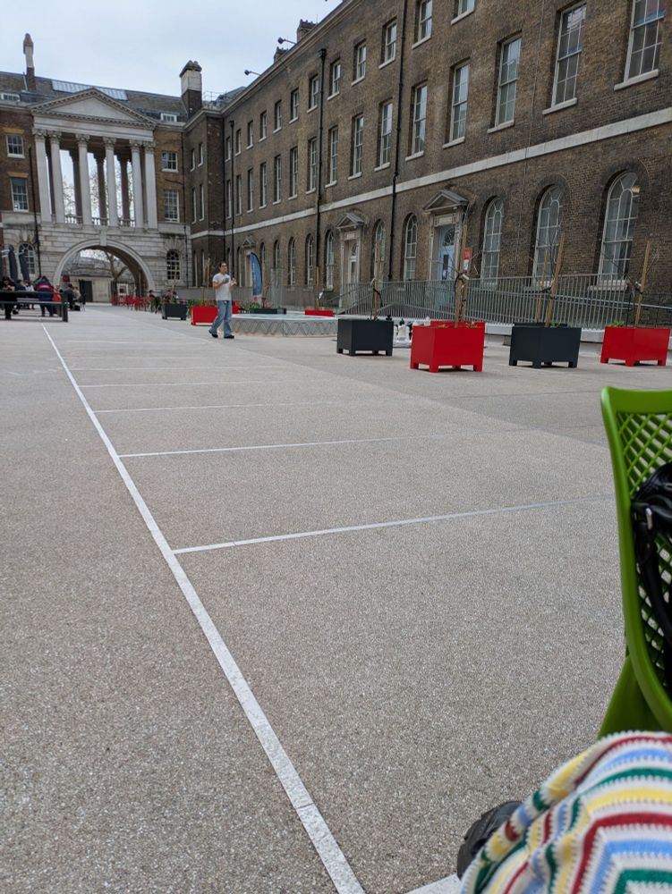 Concreted courtyard with some chairs and students. 