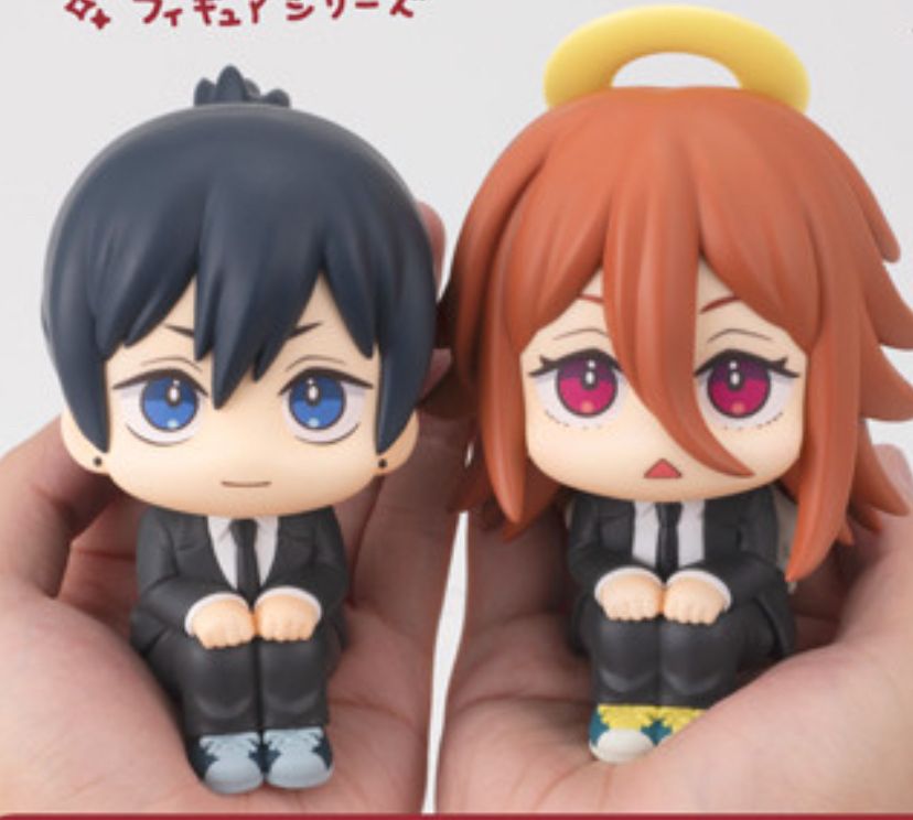 A screenshot depicting figurines of Chainsaw Man characters Hayakawa Aki (left) and Angel Devil (right) in a sitting pose with their hands on their knees.