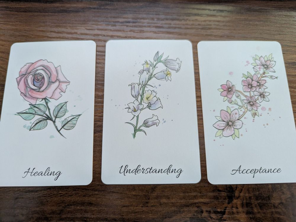 Three oracle cards: Healing (rose), Understanding (bluebells), Acceptance (cherry blossoms).