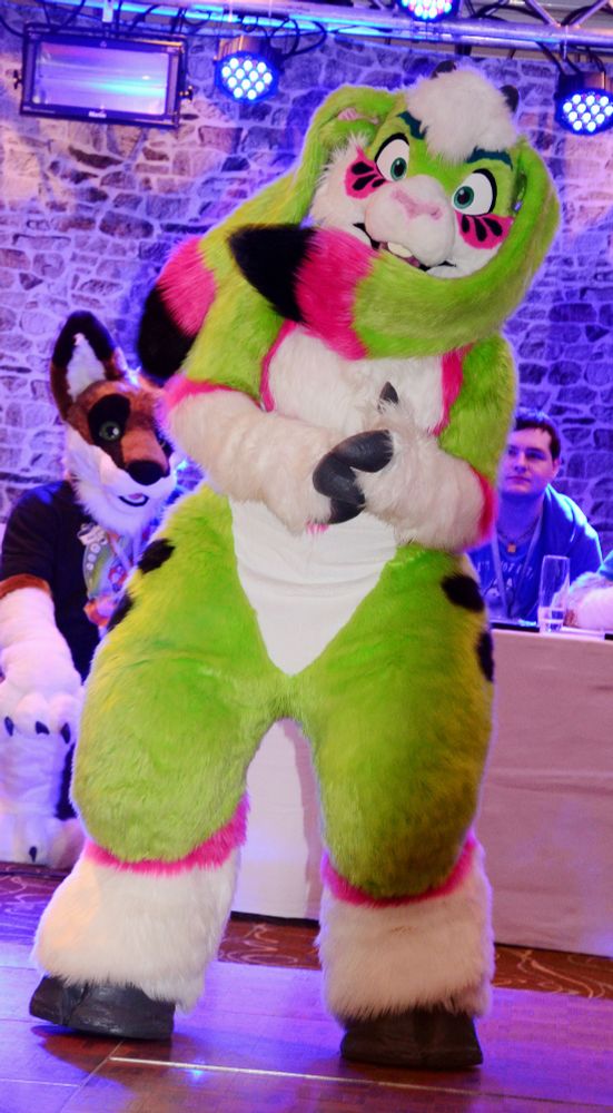 A green and white goat fursuit dancing.