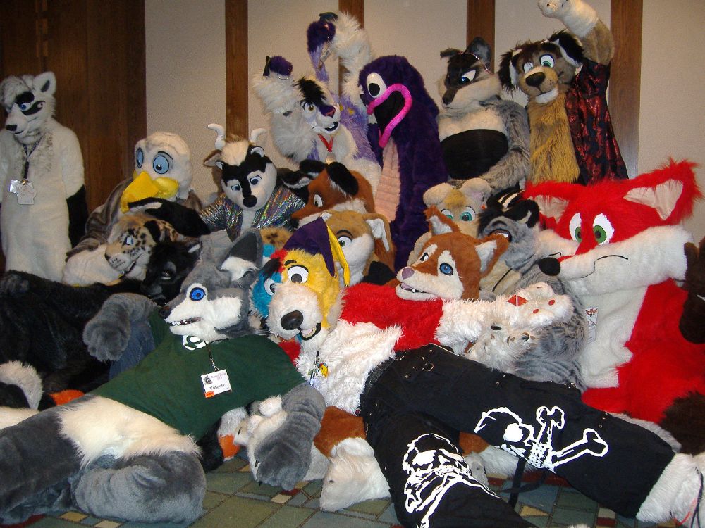 A large gathering of fursuiters in a hotel hallway.