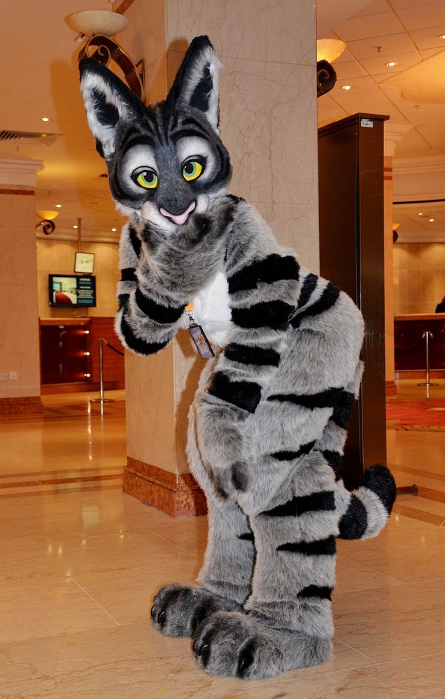 A tabby cat fursuit posing in a faux marble hotel lobby.