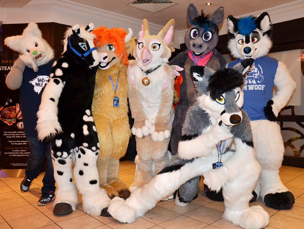 A group of fursuiters posing for a group photo in a hotel lobby.