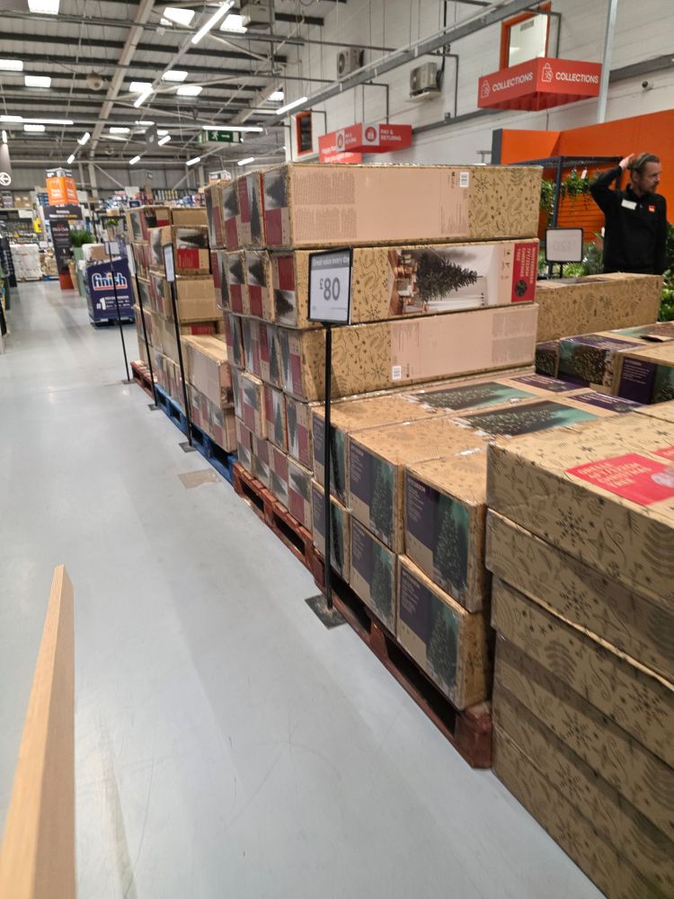Fake Christmas trees in boxes stacked for sale in a warehouse type diy store. 