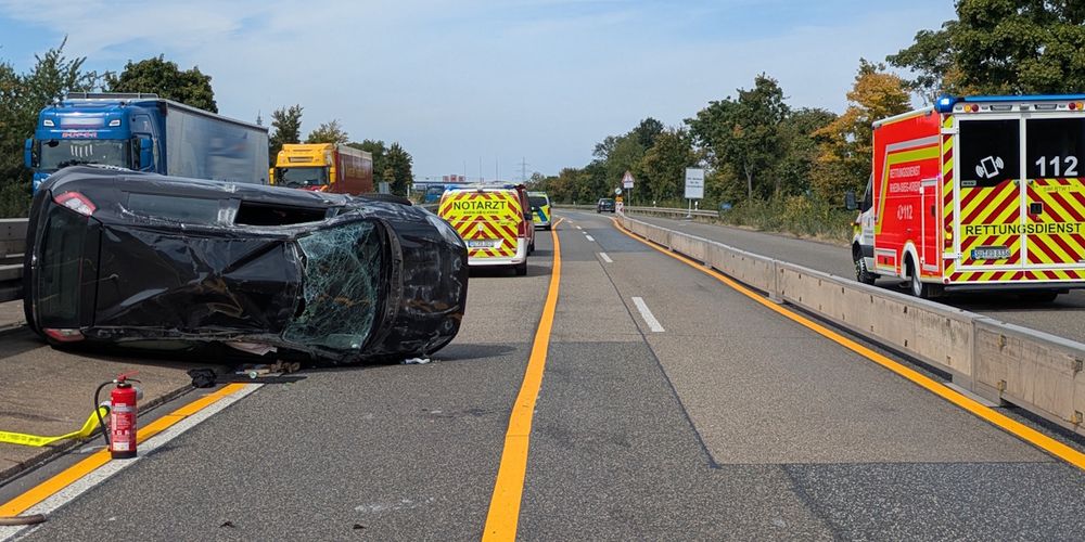 Ein verunfallter PKW liegt auf der Beifahrerseite auf der linken Spur einer Autobahn.