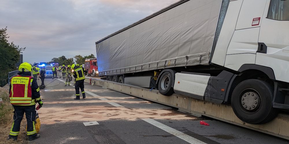 Der verunfallte LKW. Daneben stehen Feuerwehrleute und bringen Ölbindemittel aus.