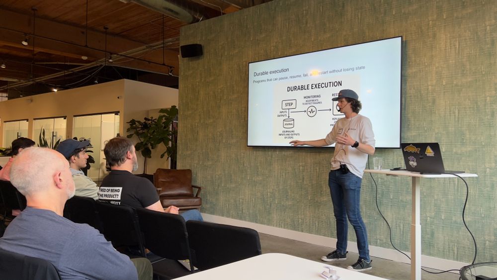 Evan is in front of a massive tv with his slides containing a diagram talking about Durable Execution.