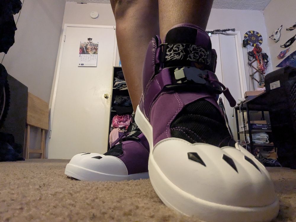 Purple high-top sneakers with white trim and lavender soles, complete with a black paw print under the toebox. The top of the toebox is designed to look like paws, complete with little black claws.