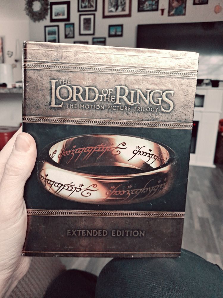 A hand is holding the box set of The Lord of the Rings movies.