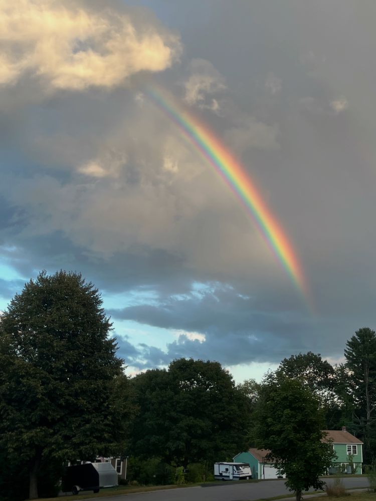 Vivid rainbow in storm clouds over a residential neighborhood