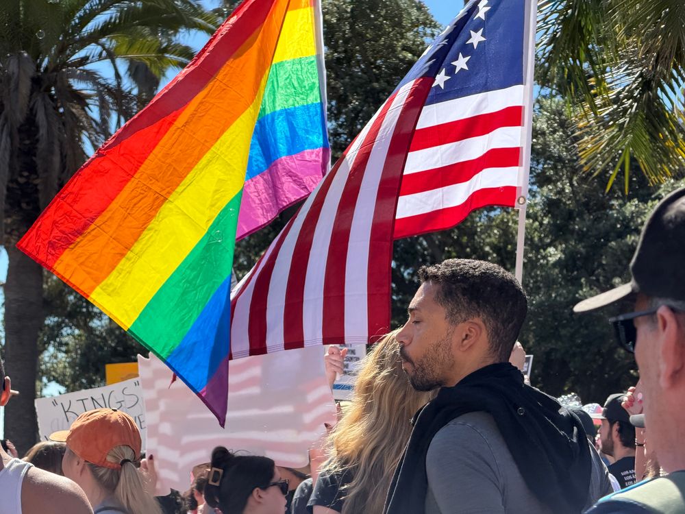 An American and a pride flag at a No Kings rally 