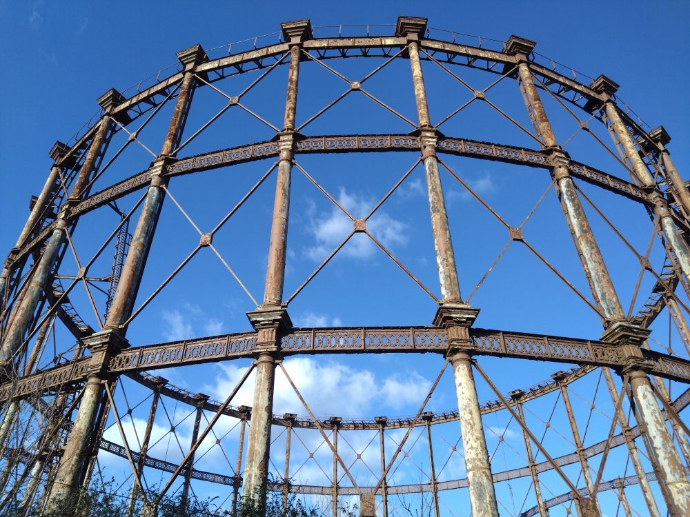 Ornate but rusted abandoned gasholder with bright blue sky