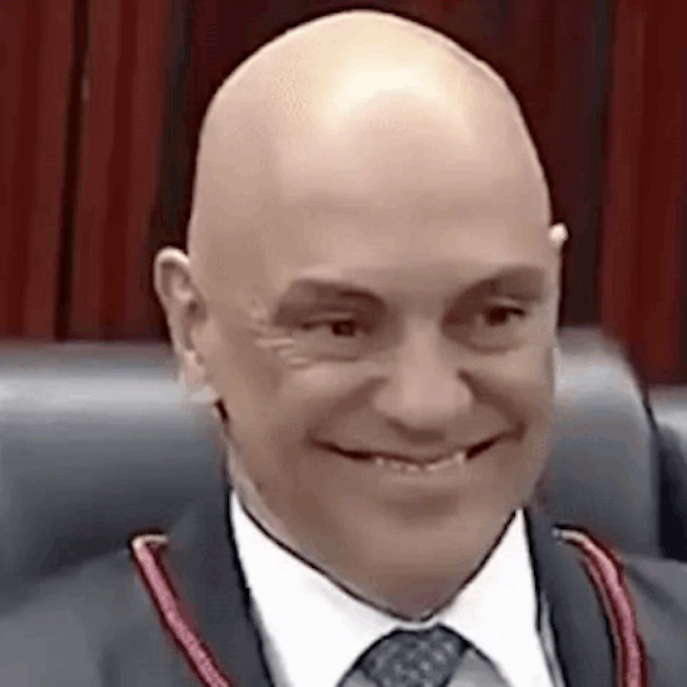 a bald man in a suit and tie is smiling and sitting in a chair .