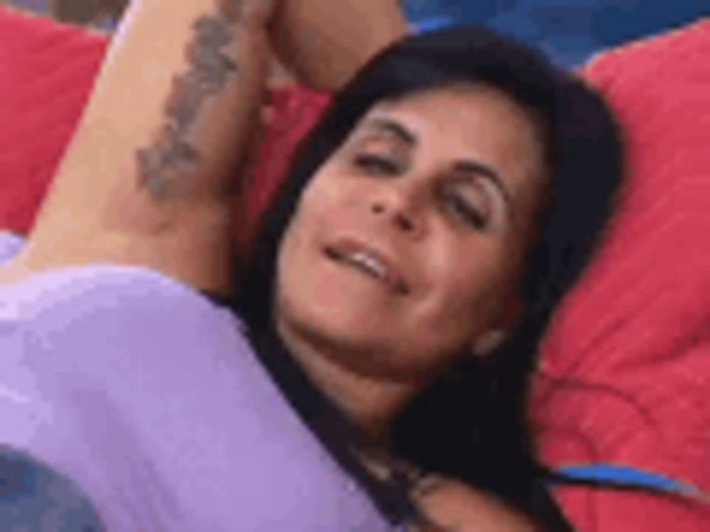 a woman with a tattoo on her arm is laying on a couch with her arms outstretched .