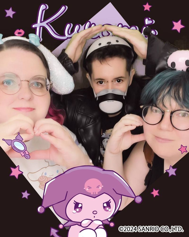 Nic, a hypermobile goth, wearing a Pochacco hat and doing a little hands-above-head pose behind Cin and Pan, their gay posse, in an exaggerated Kawaii filter in a Kuromi Sanrio digital frame