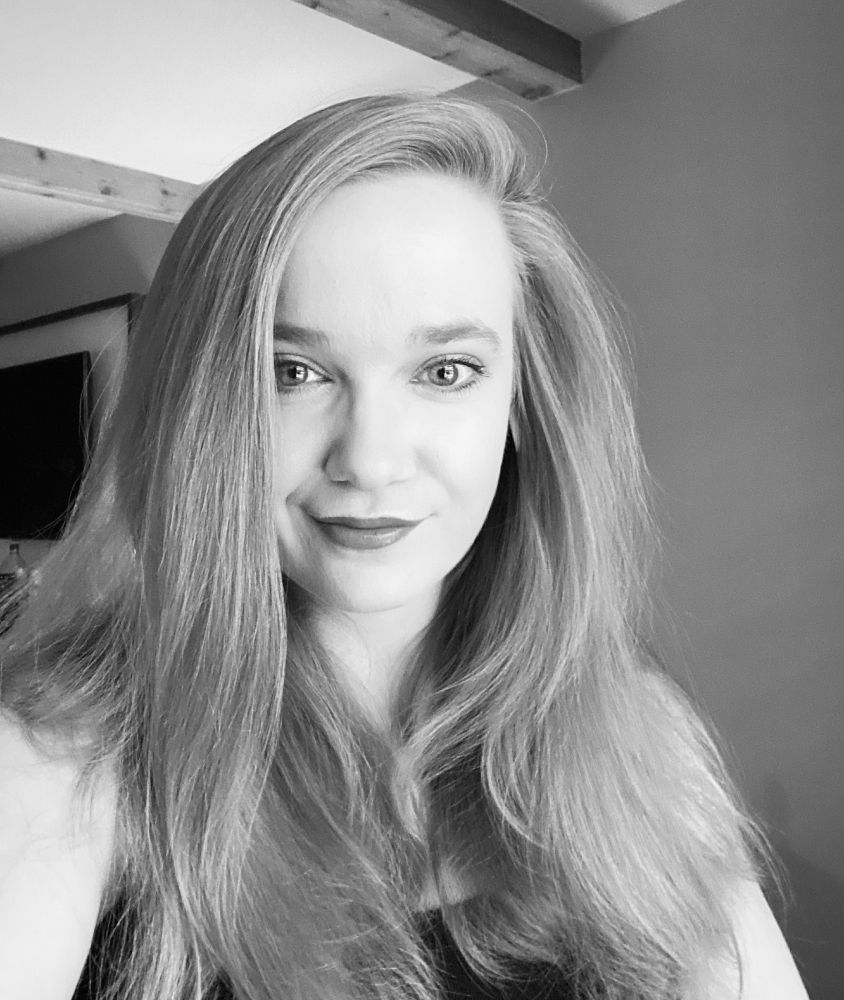 Black and white selfie of a smiling woman with long blonde hair and wearing a black tank top.