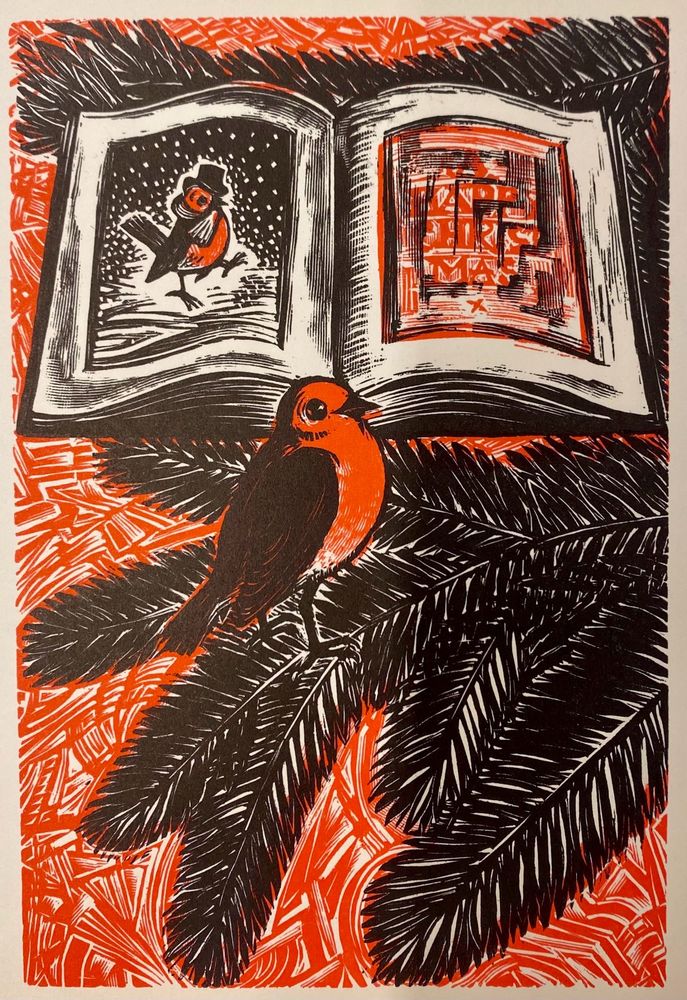 Red and black woodcut of a robin on a pine branch in front of an open book of Christmassy pictures