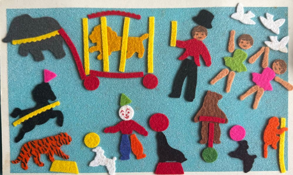 A blue fuzzy felt backing board with the felt pieces of clowns and animals from the fuzzy felt circus set stuck to it 