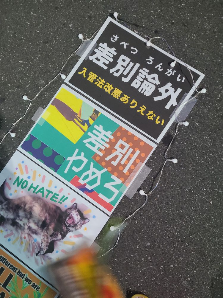 差別論外、差別やめろ、NO HATE！！とデザインされたプラカード3枚が道に並べられている写真。撤収前なので消灯しているが、アクション中は小さな豆電球状のプラスチックライトでライトアップされています