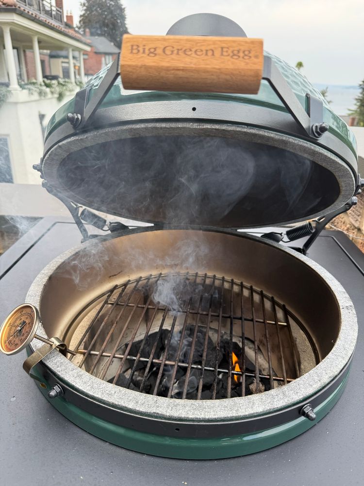 Big green egg heating up for a night of grilling. Smoke and flames