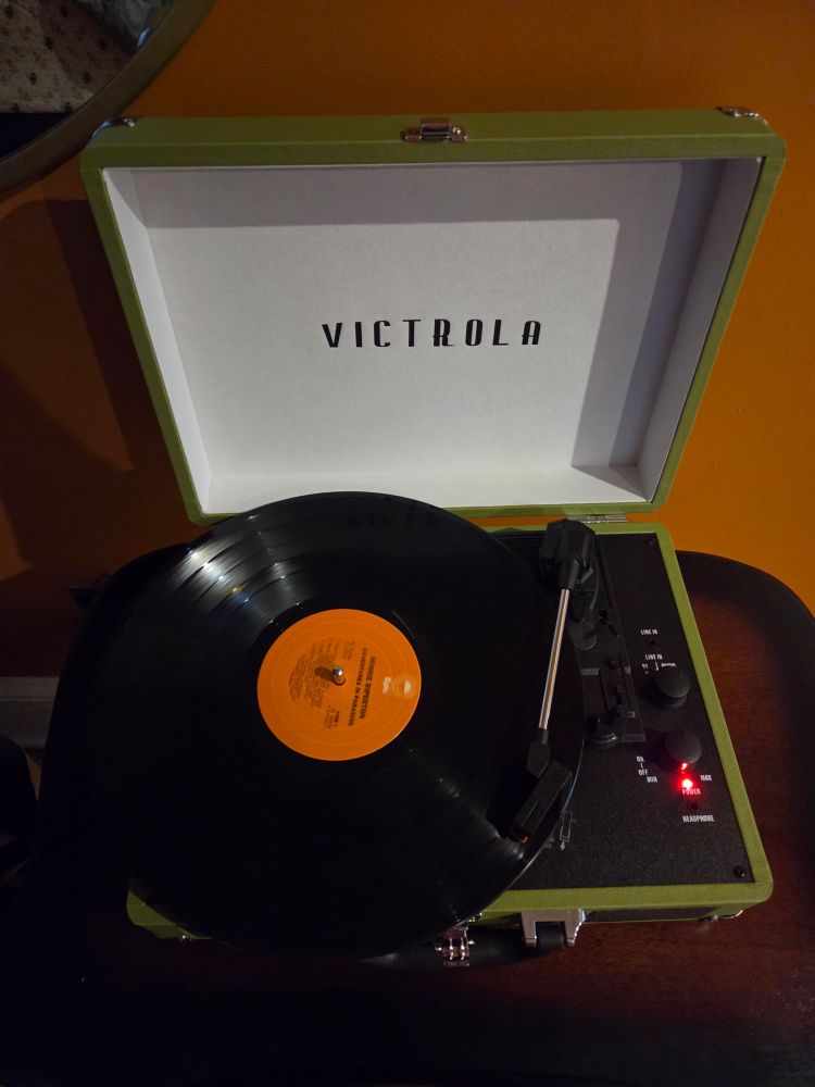 A green Victrola vinyl record player playing the album "Adventures in Paradise" by Minnie Riperton.