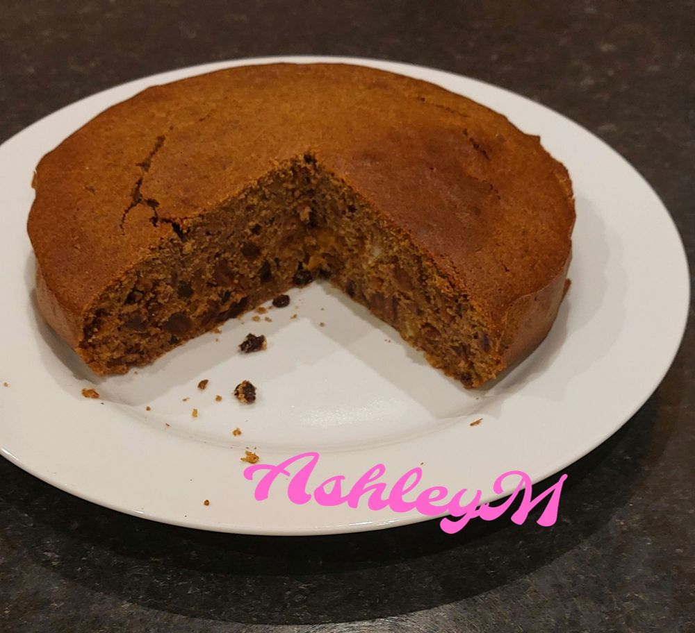 A picture of a Gluten free and sugar free fruit cake with a couple of slices already taken. It is placed on a white plate. 
