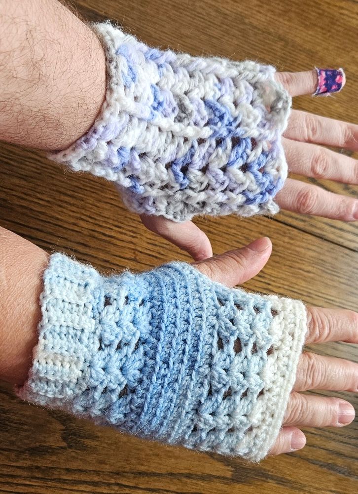 Two crochet fingerless gloves, each featuring a different pattern of shell stitches.