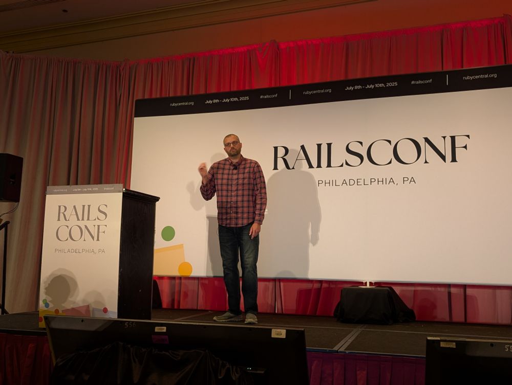 Kevin on stage in front of the RailsConf sign.