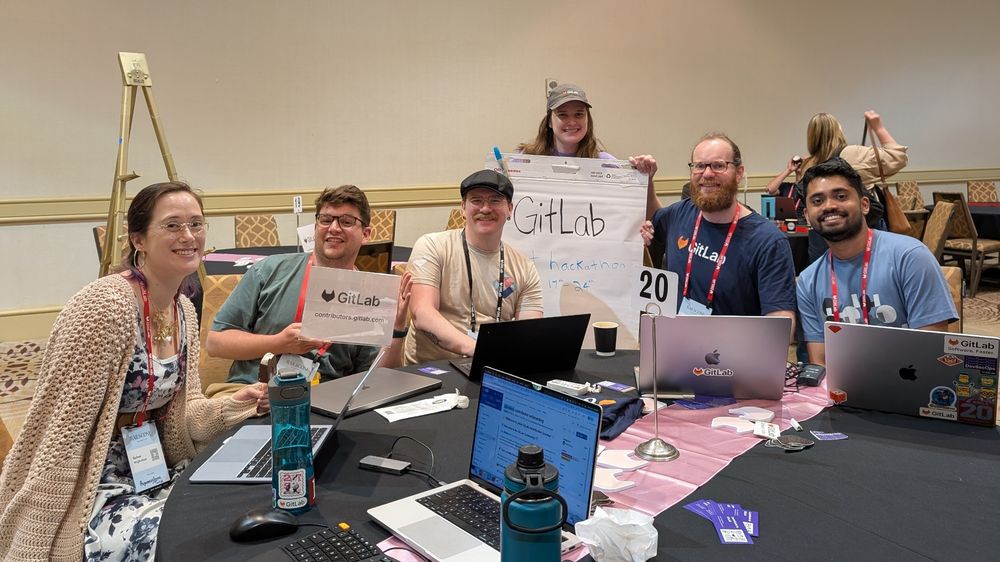 Rachael, Thomas, Josh, Ariana holding the GitLab sign, Daniel, and Manoj.