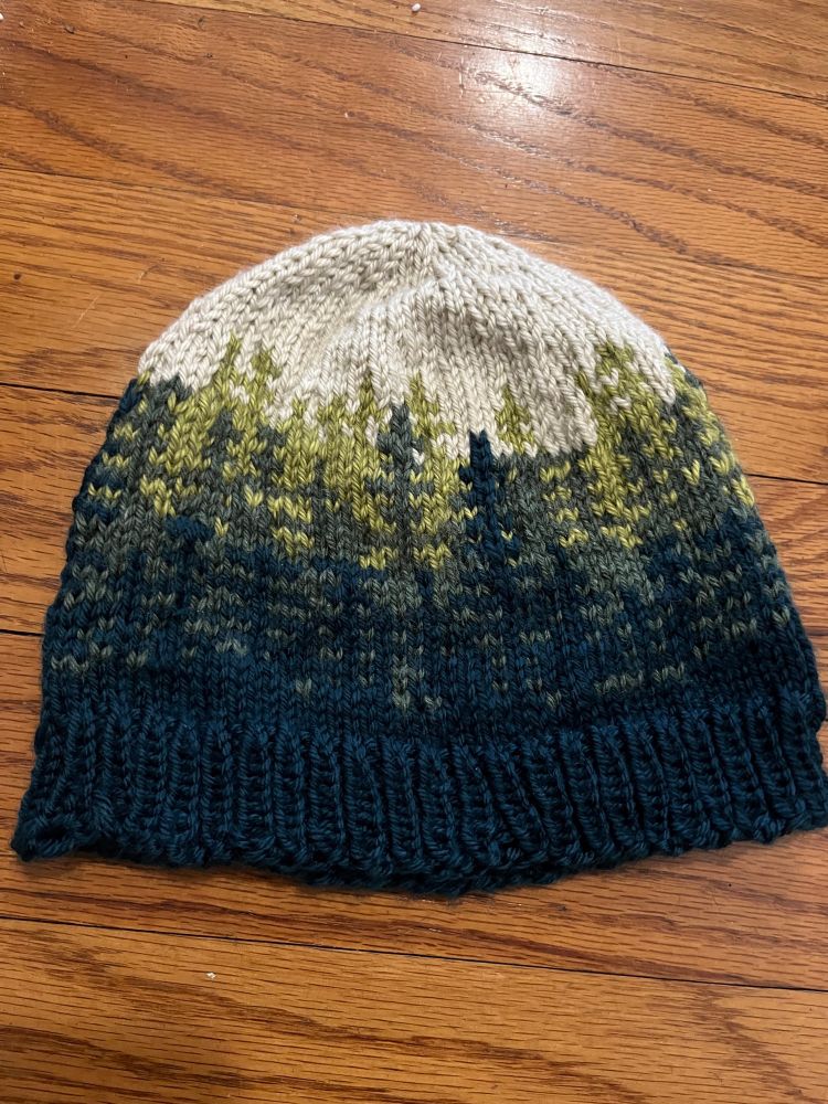 Image of a beanie hat with three layers of trees- three different colors to replicate the evergreens in Washington forests. 