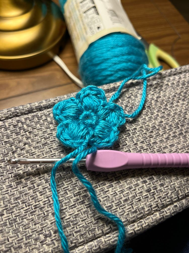 Flower puff crochet, 
Turquoise, yarn, and purple crochet needle