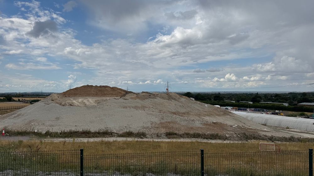 A large mound of grey soil, size of a small hill